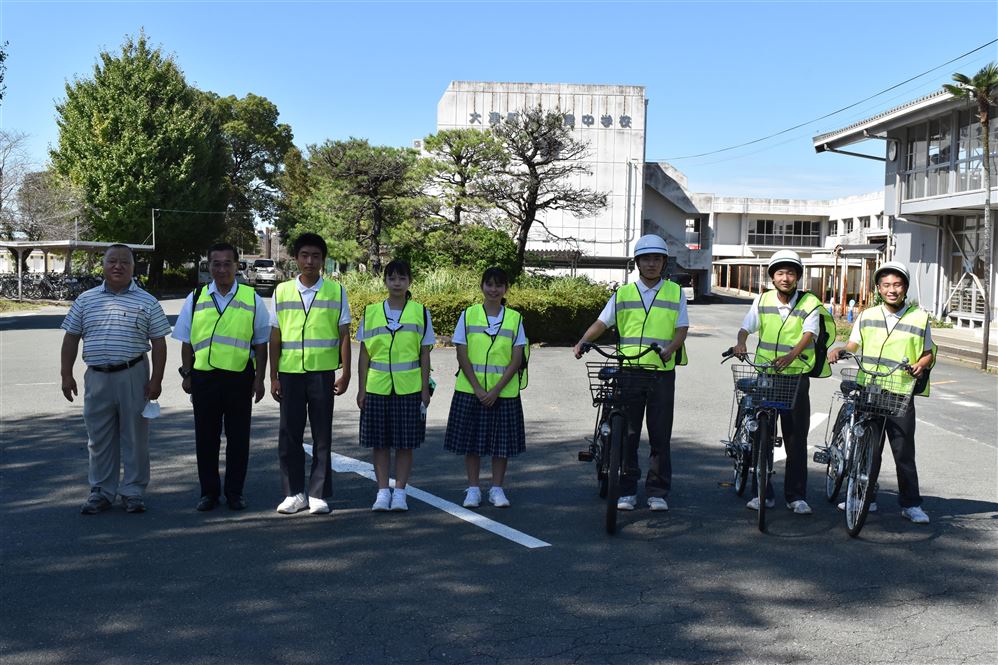 贈呈した宇佐川照孝さん(左)とベストを着用する生徒会と校長先生