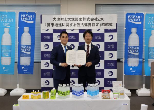 協定書を手に記念撮影に応じる大塚製薬腹支店長と金田町長