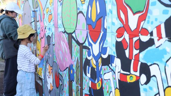 壁画を描く学生と子ども