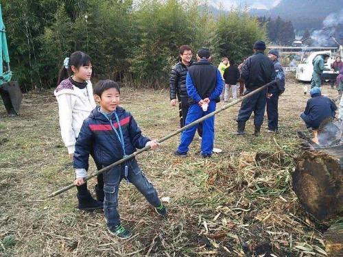 幼少期の写真、草木を燃やす傍ら棒を持ってお手伝い